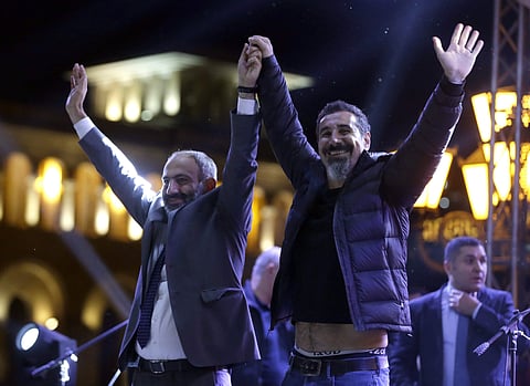 The Armenian-American singer Serj Tankian of System of a Down, right, and opposition lawmaker Nikol Pashinian greet fans during a concert in Yerevan. (AP)