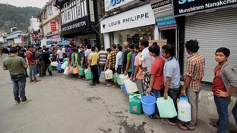 People queue up at Mall Road in Shimla to collect water from a tanker as the city faces water scarcity. (Photo | PTI)