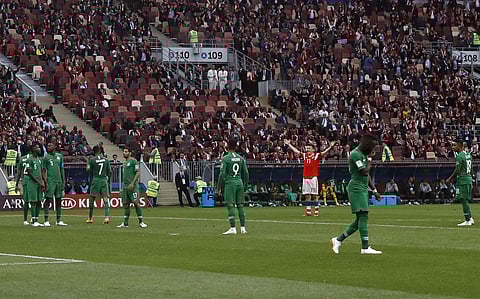 Disappointed Saudi players looks on as Russia's Alexander Golovin celebrates scoring his side's fifth goal | AP