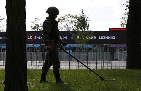A Russian soldier sweeps a grassy area with a metal detector during security checks at Luzhniki Stadium | AP