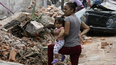 A woman holds her child as she stands next to wall turned to rubble when it collapsed during a massive earthquake, in Mexico City, Friday Sept. 8, 2017. (Photo:AP)