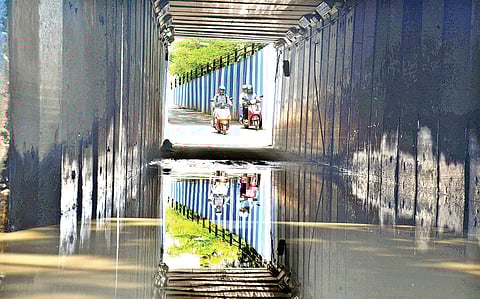 Reflection of two-wheeler riders cast on rainwater-clogged underpass connecting Cunningham Road and Sankey Road in Bengaluru on Friday. | Pushkar V