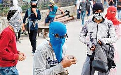 Masked youths hold stones during clashes which erupted after police tried to stop their protest rally against alleged human rights violation in Srinagar (File | PTI)
