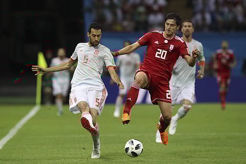 Spain's Sergio Busquets, left, fights for the ball with Iran's Sardar Azmoun during the group B match between Iran and Spain at the 2018 soccer World Cup in the Kazan Arena. | AP