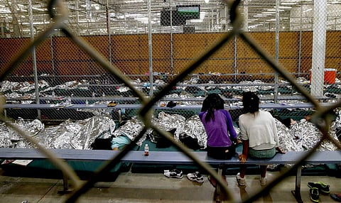 Two young girls watch a World Cup football match on a television from their holding area where hundreds of mostly Central American immigrant children are being processed and held at the U.S. Customs and Border Protection Nogales Placement Center. | AP