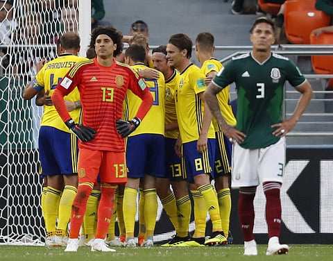 Mexico goalkeeper Guillermo Ochoa, second from left, and Mexico's Carlos Salcedo, right, react as Sweden's team players celebrate after Mexico's Edson Alvarez scored an own goal, third goal for Sweden's team, during the group F match between Mexico and Sw