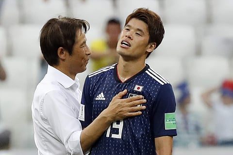 Japan's head coach Akira Nishino, left, celebrates reaching the next round with Hiroki Sakai after the group H match against Poland at the 2018 soccer World Cup at the Volgograd Arena. | AP