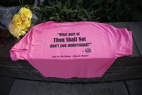 A shirt and flowers rest near the scene of a shooting at The Capital Gazette newspaper office, Friday, June 29, 2018, in Annapolis, Md. A man armed with smoke grenades and a shotgun attacked journalists in the building Thursday, killing several people bef