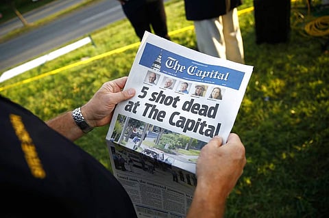 Steve Schuh, county executive of Anne Arundel County, holds a copy of The Capital Gazette near the scene of a shooting at the newspaper's office. (Photo| AP)