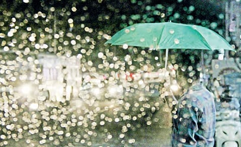 A man shields himself with an umbrella during heavy rain at Banjara Hills, in Hyderabad on Sunday | r satish babu