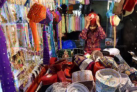 A boy trying out a red coloured taqiyah(skullcap) in Laad Bazaar. (EPS | R.Satish Babu)