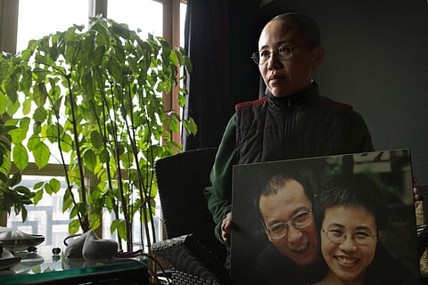 Liu Xia, wife of 2010 Nobel Peace Prize winner Liu Xiaobo, poses with a photo of her and her husband during her first interview in more than two years at her home in Beijing, China. (Photo | AP)