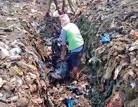 Karimnagar Municipal Corporation workers digging out the body of the man, who died in an accident, from a local dump yard on Monday | Express