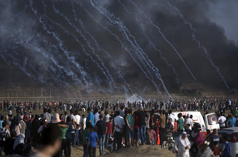 Teargas canisters fired by Israeli troops fall over Palestinians during a protest at the Gaza Strip | AP