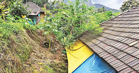 A chunk of earth is poised dangerously over the roof of a house at Four Cent Colony in Sathrapaddy