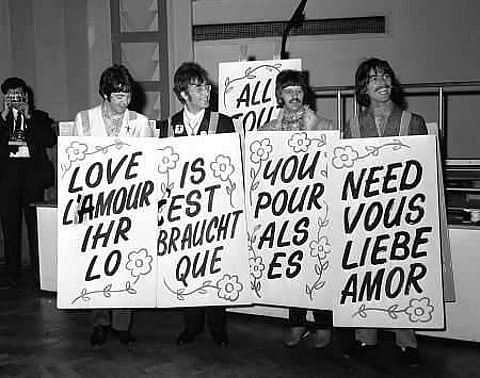 A 1967 photo of the Beatles holding up signs that say 'All you need is love' in different languages. (Photo | IMDB)
