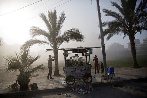 Two Palestinian men photograph a damaged hot drink street vending carte following an Israeli airstrike hits a governmental building in Gaza City. (AP)