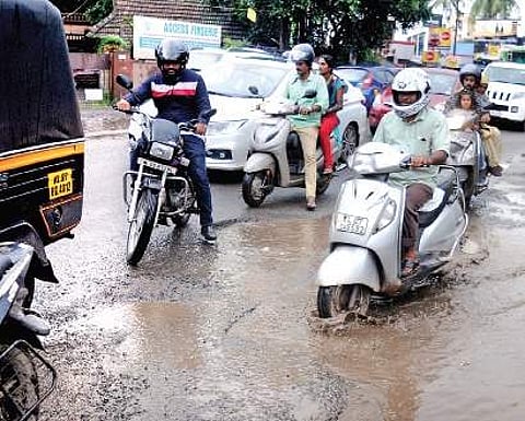 Motorists trying to negotiate the waterlogged pothole at Alinchuvadu