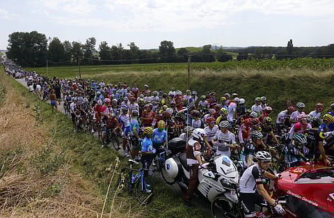 Riders wait on the road after a farmer's protest interrupted the sixteenth stage of the Tour de France. (Photo | AP)