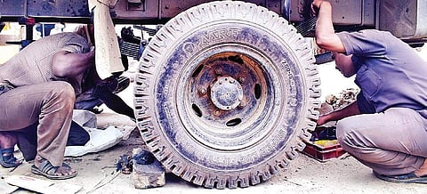 Lorry drivers repair their vehicle’s tyre on Day 4 of the nationwide truckers’ strike in Bengaluru on Monday | Pandarinath B