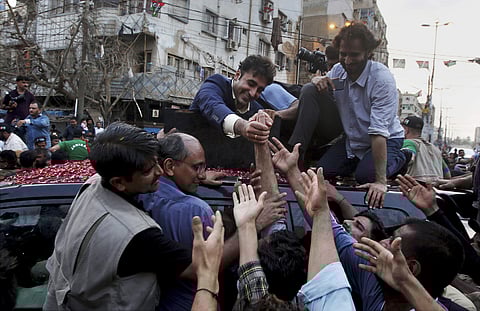 In this July 1, 2018, file photo, Bilawal Bhutto Zardari, center, leader of the Pakistan Peoples party shakes hands with supporters during a rally for the July 25 general elections, in Karachi, Pakistan. As Pakistanis prepare to make history on Wednesday