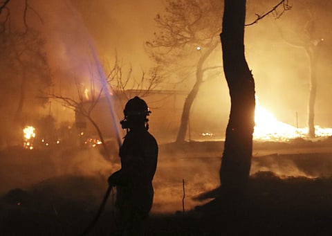 A firefighter sprays water on the fire in the town of Mati, east of Athens, Monday, July 23, 2018. | Associated Press