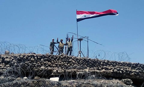 n this Tuesday, July 17, 2018, file photo, released by the Syrian official news agency SANA, Syrian troops flash the victory sign next to the Syrian flag in Tell al-Haara, the highest hill in the southwestern Daraa province, Syria. Israel shot down a Syri