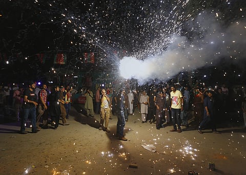 A supporter of Pakistani politician Imran Khan, chief of Pakistan Tehreek-e-Insaf party, releases fireworks to celebrate projected unofficial results announced by television channels indicating their candidates' success in the parliamentary elections in I