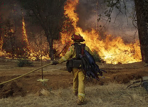 A firefighter walks to flames as a wildfire advances onto a residential district Saturday in Redding, California. (Photo | AP)