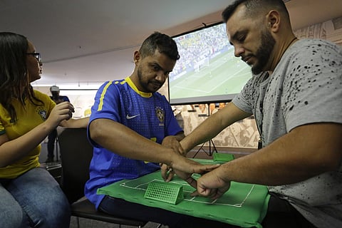 Brazil soccer fan Carlos Junior, who is both deaf and blind, experiences the World Cup match between Brazil and Mexico with the help of an interpreter . (AP)