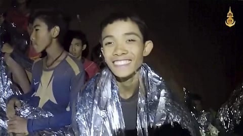 In this July 3, 2018, image taken from video provided by the Royal Thai Navy Facebook Page, a Thai boy smiles as Thai Navy SEAL medic help injured children inside a cave in Mae Sai, northern Thailand. | AP