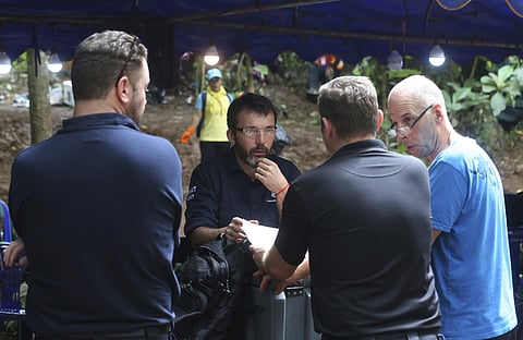 Australian Federal Police and Defense Force personnel talk each other near a cave where 12 boys and their soccer coach are trapped, in Mae Sai, Chiang Rai province, in northern Thailand, Thursday, July 5, 2018. With more rain coming, Thai rescuers are rac