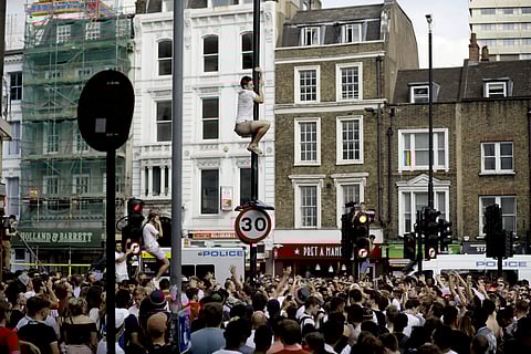 An England fan climbs a lamppost as they celebrate on the streets in the London Bridge area after England won their FIFA World Cup quarterfinal match against Sweden | AP
