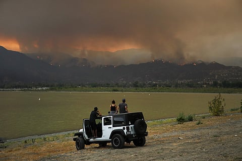 Onlookers watch as a wildfire burns near Lake Elsinore, Calif., Wednesday, Aug. 8, 2018. Evacuations have been ordered for several small mountain communities near where a forest fire continues to grow in Southern California. (Photo | AP)