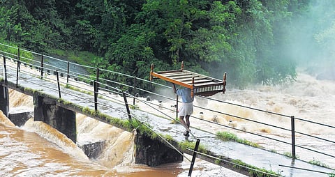 A flood-affected man carries the last of his belongings across the overflowing Deviyar river in Valara near Adimaly on Thursday. | (A Sanesh | EPS)
