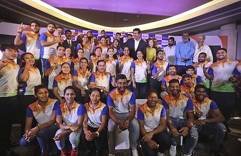 Indian Sports Minister Rajyavardhan Singh Rathore, center right in black suit, stands with the Indian contingent for the 18th Asian Games during their send-off ceremony in New Delhi. (Photo | AP)