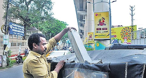 Auto driver Joy picking up the piece of concrete that fell from the Kochi Metro rail pillar near the Lisie metro station on Tuesday evening | A SANESH