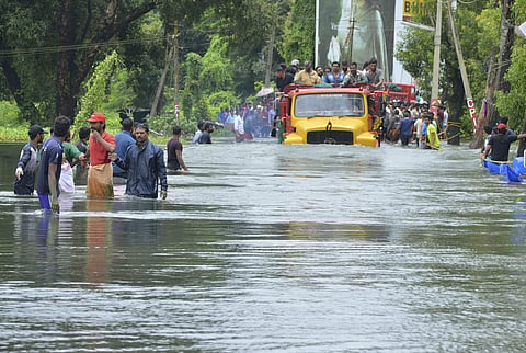 A truck carries people past a flooded road in Thrissur, Kerala. (Photo | AP)