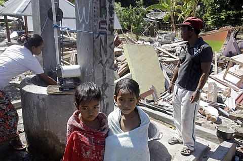 Children cover themselves with towels after a bath near their home destroyed by last week's earthquake in North Lombok, Indonesia. (Photo | AP)