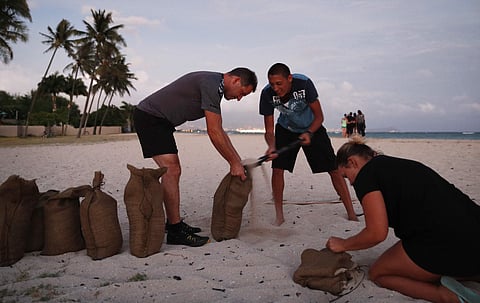 People fill up sand bags that will be used to help protect their home in preparation for Hurricane Lane | AP