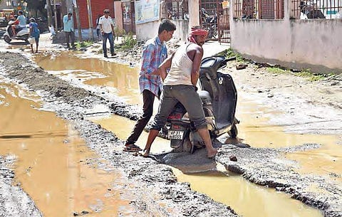 A two-wheeler and a lorry got stuck in a ditch dug up for laying underground sewage lines by VMC near Museum Road in Vijayawada on Wednesday | R V K Rao