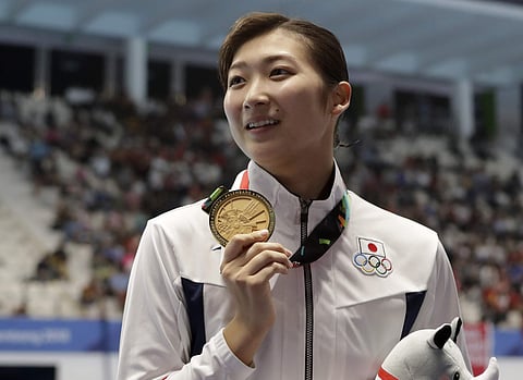 Japan's Rikako Ikee holds up her gold medal after winning the women's 100m butterfly final during swimming competition at the 18th Asian Games. (Photo | AP)