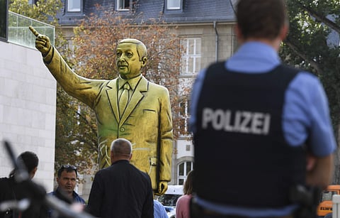 Police and passersby surround a statue showing Turkish President Erdogan which is part of the art festival 'Wiesbaden Biennale' in Wiesbaden, western Germany, Tuesday, Aug. 28, 2018. (Arne Dedert/dpa via AP)