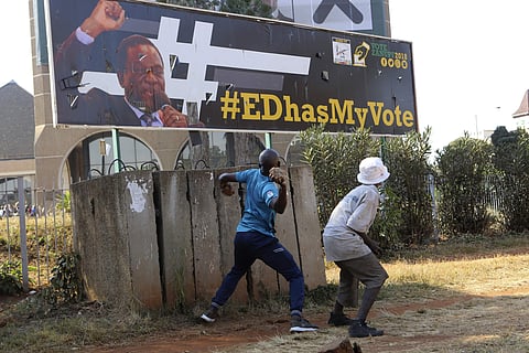 An opposition party supporter throws a rock aimed at Zimbabwean President Emmerson Mnangagwa's election campaign poster in Harare, Zimbabwe, Wednesday, Aug. 1, 2018. | AP
