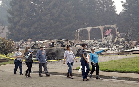 Carol Smith, far right in blue, her daughter Suzie Scatena, third from right, and husband Tim, third from left, tour their fire-ravaged neighborhood along with support crews Thursday, Aug. 2, 2018, in Redding, Calif. The Smith's home of 30 years was destr