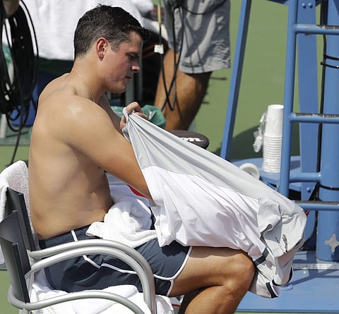 Milos Raonic, of Canada, changes his shirt during a changeover in his match against Gilles Simon, of France, during the second round of the U.S. Open | AP