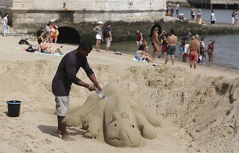 A man sprays water on his sand sculpture by the Tagus riverbank in Lisbon Thursday, Aug. 2 2018. The temperature in Lisbon reached 39 degrees Celsius, 102.2 Fahrenheit, on Thursday and is expected to keep rising over the next few days. | AP