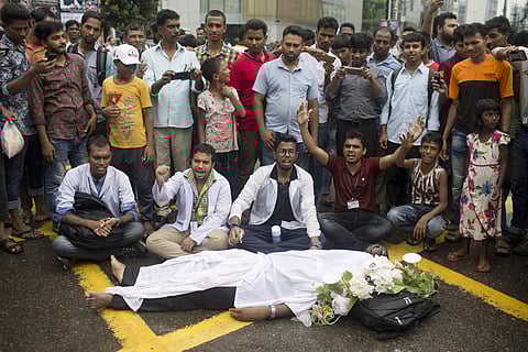 A Bangladeshi student enact as a dead while others shout slogans a during a protest in Dhaka. (Photo | AP)