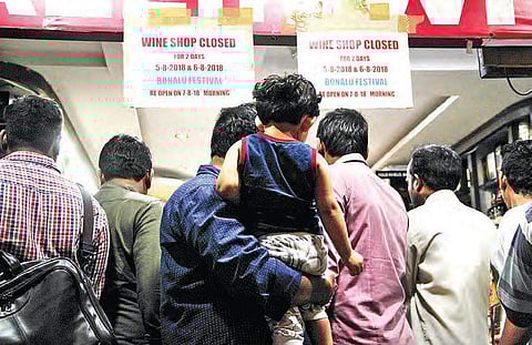 No stopping this man: A father takes a child to buy liquor during rush hour in Hyderabad on Saturday, as wine shops will be closed on Sunday and Monday in view of Bonalu festival | R Satish Babu