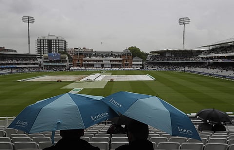 People shelter under umbrellas as rain delays the start of play on the first day of the second test match between England and India at Lord's cricket ground in London. (Photo | AP)